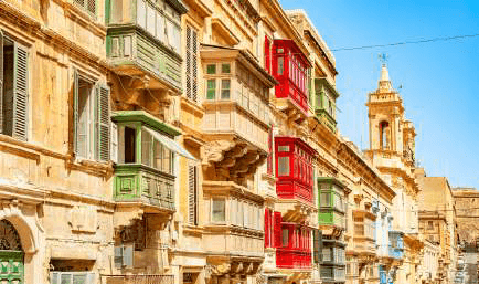 A Malta street of limestone townhouses with painted balconies